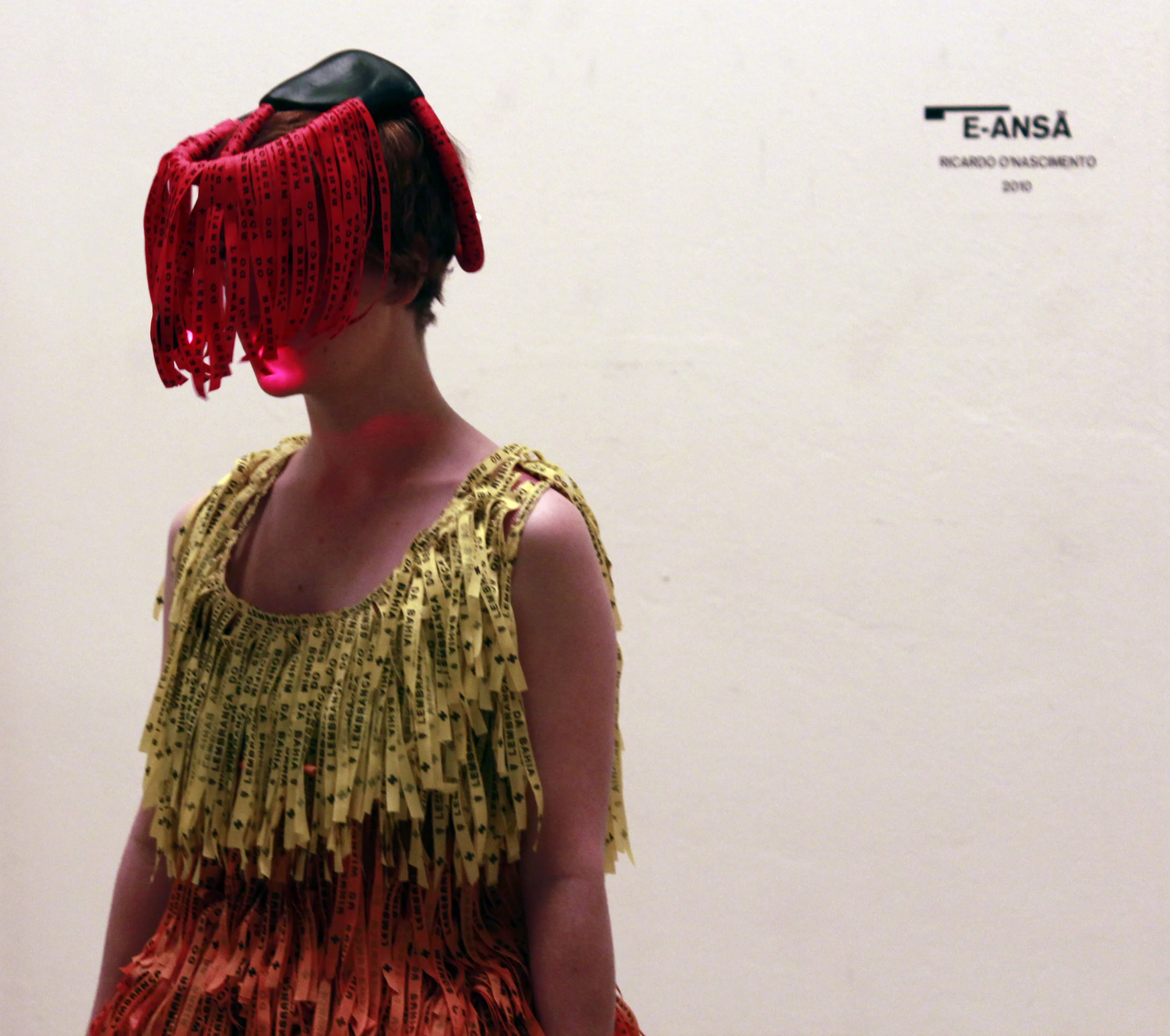 Side view of the e-Ansã dress and its layers of red, yellow and orange ribbons