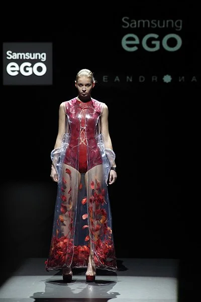 Model wearing a transparent red and clear full-length look from 083