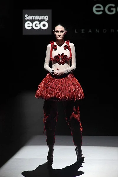 Model wearing a red feathered skirt and sculptural white top from 083