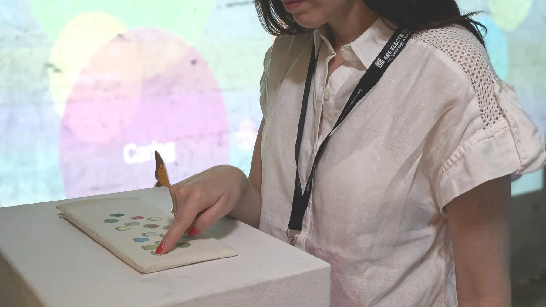 A visitor pressing one of the coloured wellbeing keys while standing in front of the projection