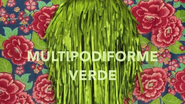 Video still showing the green ribbon sculpture with the title Multipodiforme Verde