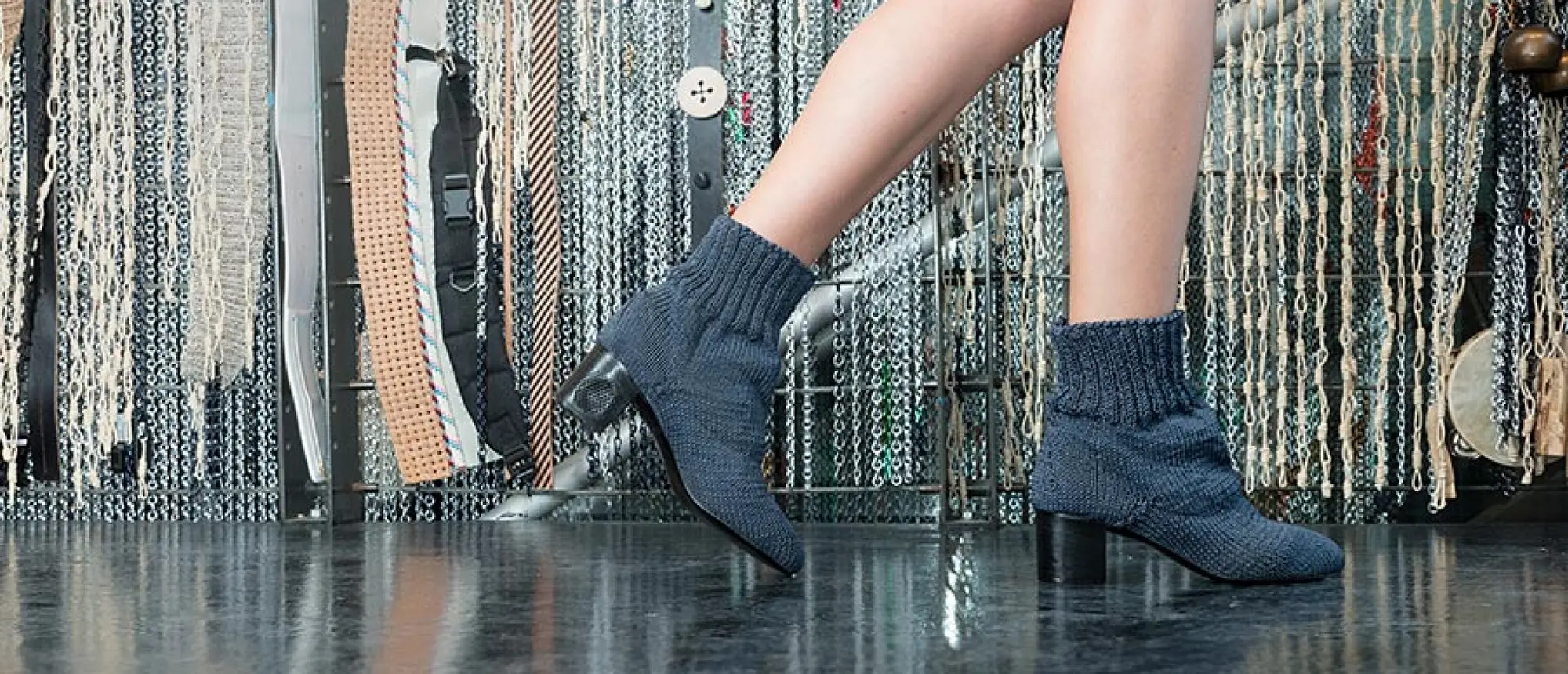 A visitor wearing dark knitted Recording Shoes in the Sonic Fabric installation