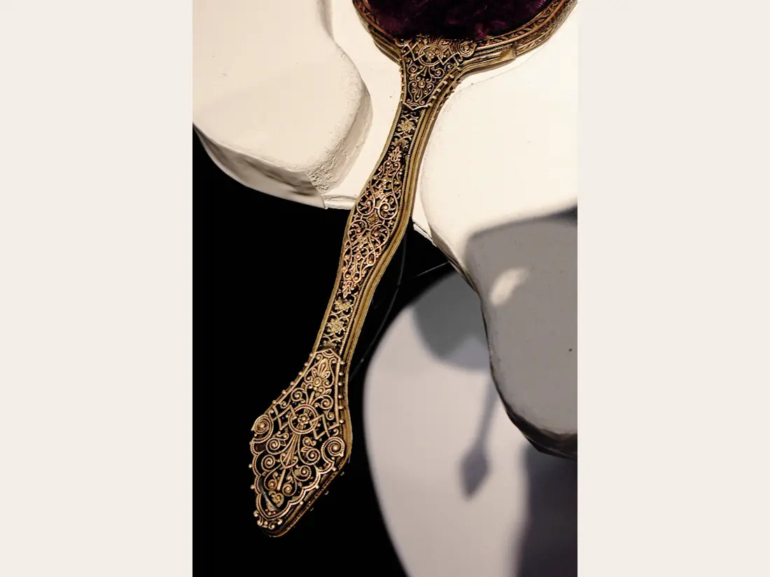An ornate hand mirror and hairbrush displayed beside the Untangle Me dress